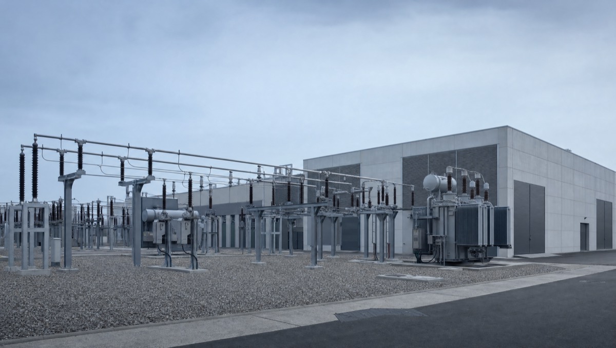 An electrical switchyard with transformers, disconnect switches and busbars in orderly rows.